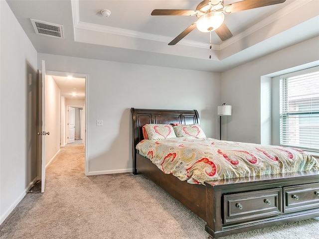 bedroom with ceiling fan, light colored carpet, ornamental molding, and a tray ceiling