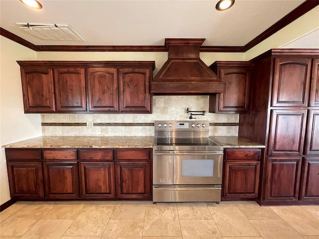 kitchen with light stone counters, decorative backsplash, stainless steel range with electric stovetop, custom range hood, and ornamental molding