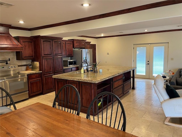kitchen featuring french doors, a sink, visible vents, appliances with stainless steel finishes, and premium range hood