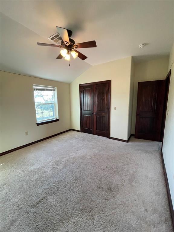 unfurnished bedroom with ceiling fan, vaulted ceiling, baseboards, and light carpet