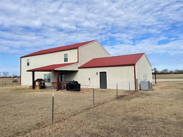 back of house with fence, central air condition unit, and metal roof