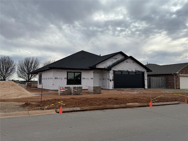 property under construction featuring driveway, an attached garage, and fence