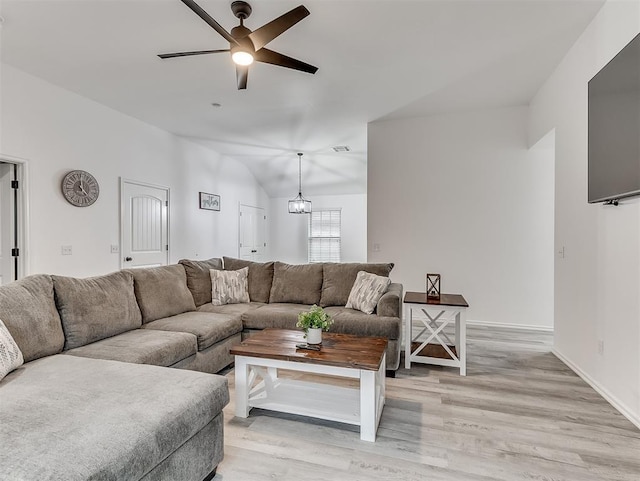 living room featuring ceiling fan with notable chandelier, lofted ceiling, and light hardwood / wood-style floors