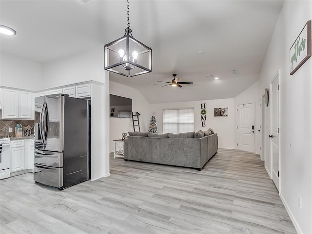 kitchen featuring white stove, stainless steel fridge with ice dispenser, hanging light fixtures, white cabinets, and backsplash