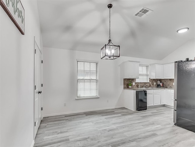 kitchen featuring tasteful backsplash, decorative light fixtures, light hardwood / wood-style flooring, stainless steel refrigerator, and white cabinets