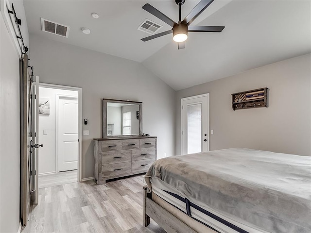 bedroom with vaulted ceiling, a barn door, ceiling fan, and light hardwood / wood-style flooring