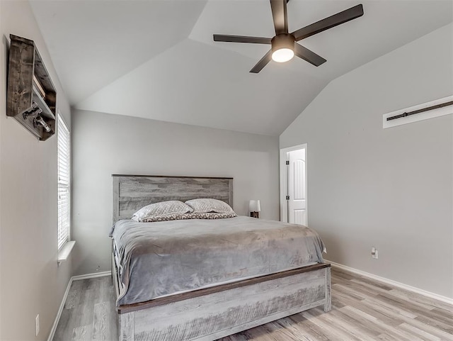 bedroom with ceiling fan, lofted ceiling, and light wood-type flooring