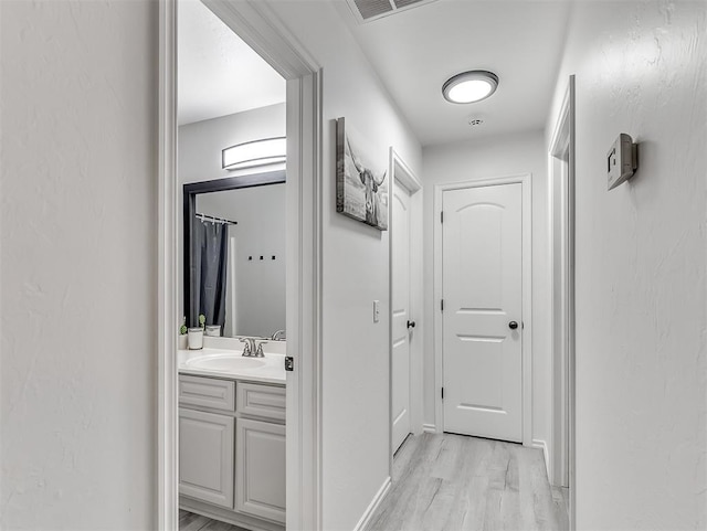 hallway with light hardwood / wood-style floors and sink