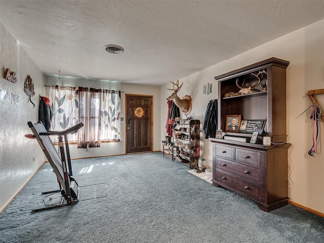 workout room with a textured ceiling and light carpet