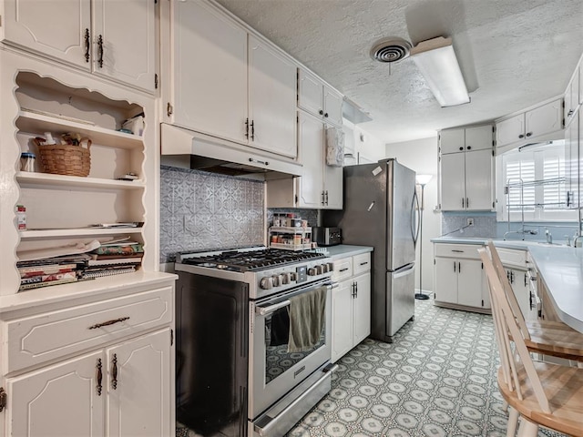 kitchen featuring white cabinets, decorative backsplash, stainless steel appliances, and a textured ceiling