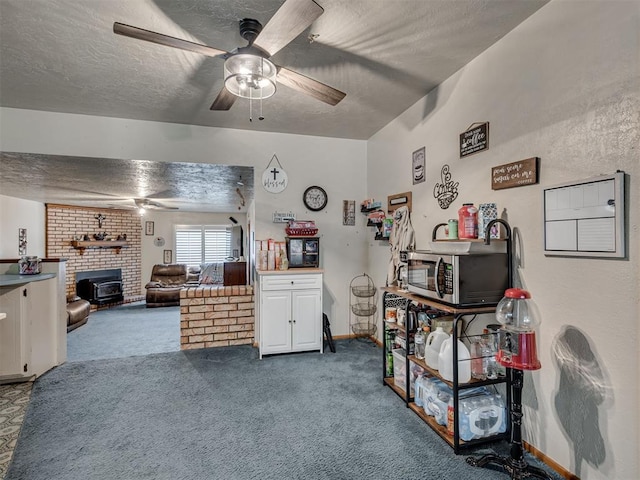 bedroom featuring carpet flooring, a textured ceiling, a wood stove, and ceiling fan