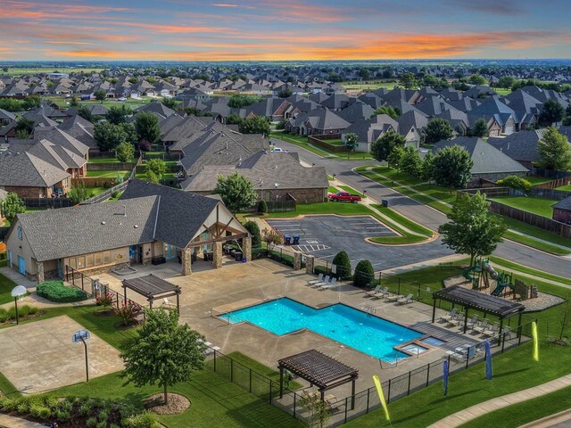 pool at dusk featuring a residential view and fence