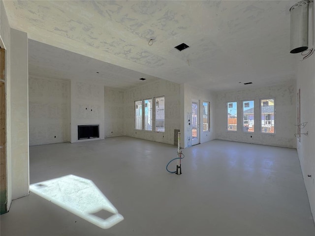 unfurnished living room with a wealth of natural light, a fireplace, and concrete floors