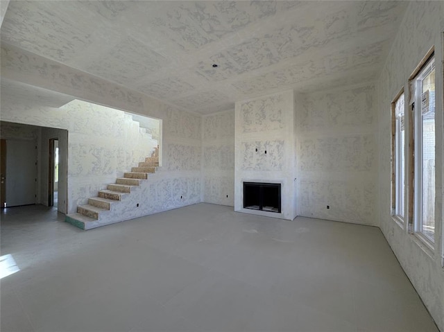 unfurnished living room featuring stairs, a fireplace, and concrete flooring