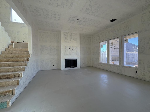 unfurnished living room featuring stairs and a fireplace