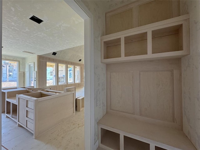 mudroom with a textured ceiling and wallpapered walls