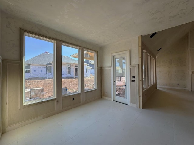 empty room featuring a sunroom and baseboards