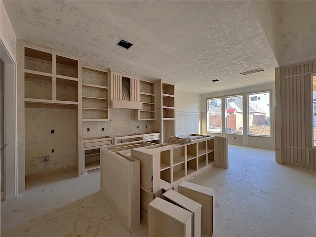 kitchen with a textured ceiling, open shelves, visible vents, and a center island