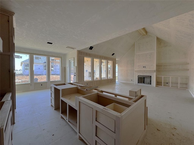 interior space with lofted ceiling, a fireplace, open floor plan, and a textured ceiling