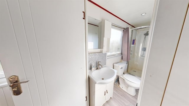 bathroom with wood-type flooring, vanity, toilet, and a shower with shower door