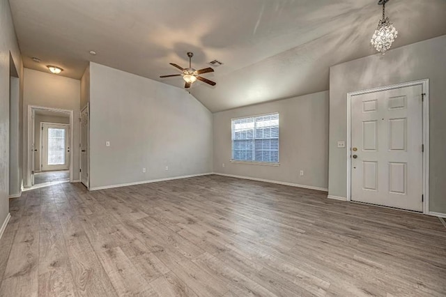 unfurnished living room featuring ceiling fan with notable chandelier, light wood-type flooring, and vaulted ceiling