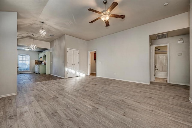 unfurnished living room with hardwood / wood-style flooring, ceiling fan with notable chandelier, and lofted ceiling