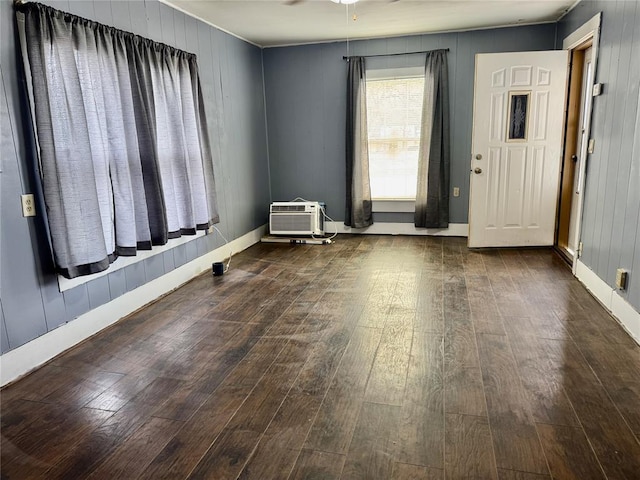 spare room with a wall unit AC, ceiling fan, dark hardwood / wood-style floors, and wood walls