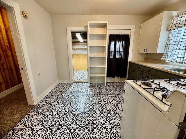 kitchen with white range with gas stovetop, sink, and white cabinetry