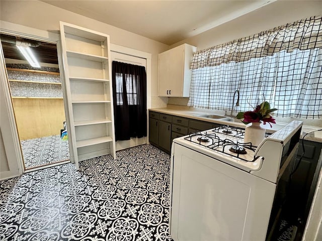 kitchen with white range with gas cooktop, white cabinets, and sink