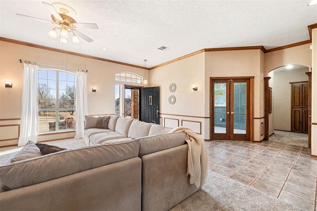 living room with french doors, ceiling fan, ornamental molding, a textured ceiling, and light tile patterned flooring