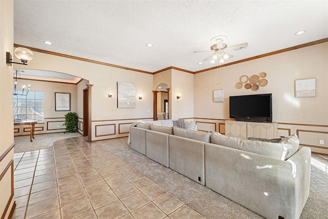 living room with light carpet, a textured ceiling, ceiling fan with notable chandelier, and ornamental molding