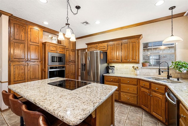 kitchen featuring sink, a center island, hanging light fixtures, appliances with stainless steel finishes, and ornamental molding