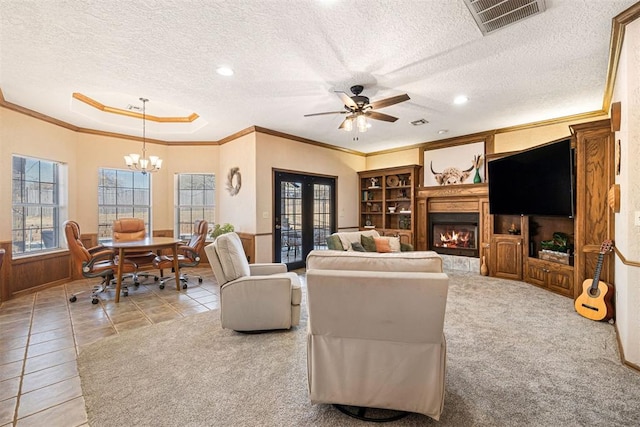 living room featuring ceiling fan with notable chandelier, a textured ceiling, light colored carpet, and crown molding