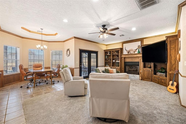 carpeted living room featuring ceiling fan with notable chandelier, a textured ceiling, and ornamental molding