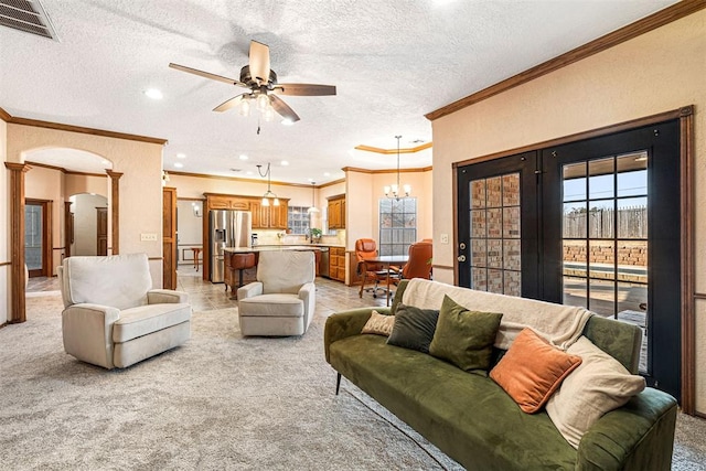 living room with light carpet, ceiling fan with notable chandelier, a textured ceiling, and ornamental molding