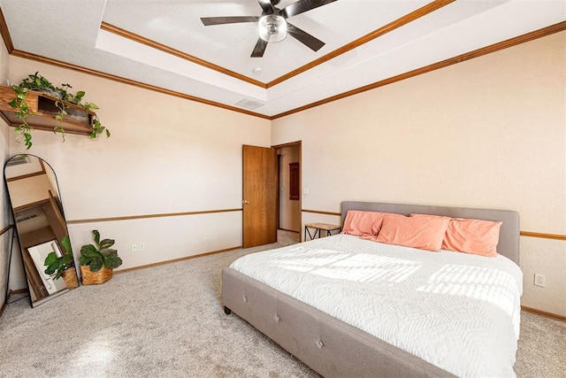 carpeted bedroom featuring a tray ceiling, ceiling fan, and ornamental molding