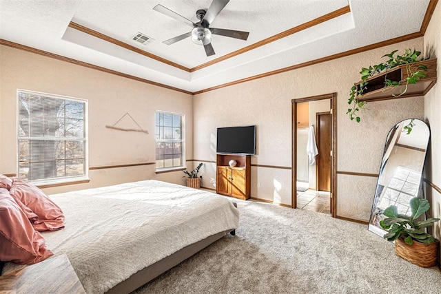 carpeted bedroom with a textured ceiling, ceiling fan, crown molding, and a tray ceiling