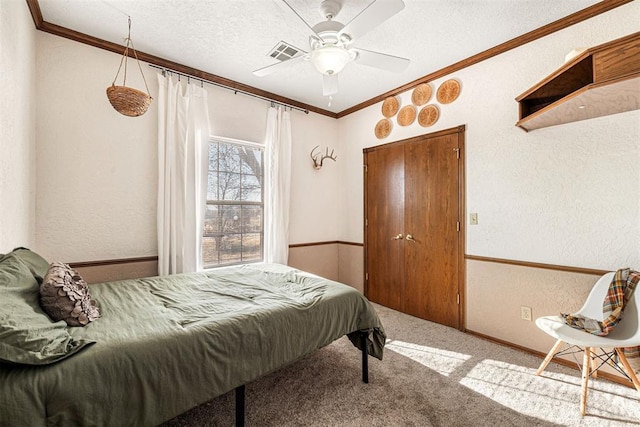 bedroom featuring carpet, a textured ceiling, ceiling fan, and ornamental molding