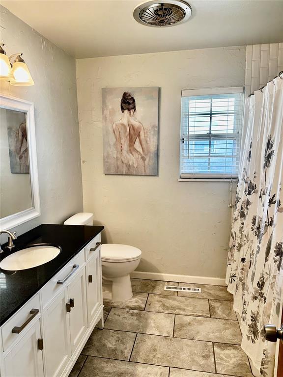 bathroom with curtained shower, vanity, and toilet