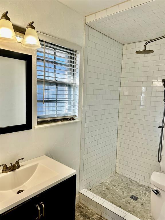 bathroom featuring vanity, toilet, and tiled shower