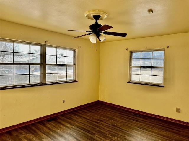 unfurnished room with ceiling fan, dark wood-type flooring, and a healthy amount of sunlight