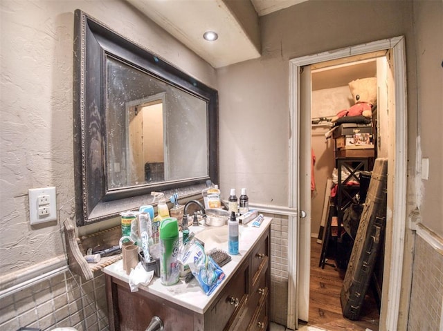 bathroom with wood-type flooring, vanity, and tile walls