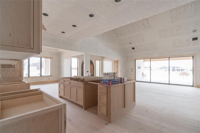 kitchen featuring light hardwood / wood-style floors, light brown cabinets, and high vaulted ceiling