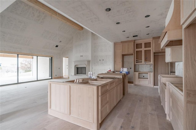 kitchen featuring high vaulted ceiling, light brown cabinets, a center island, and light wood-type flooring