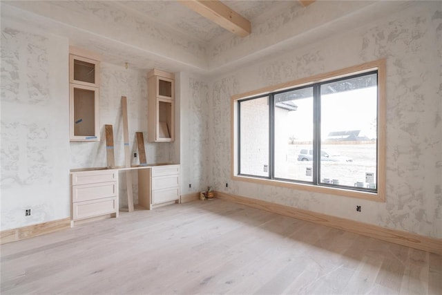 interior space featuring beam ceiling, a wealth of natural light, and light hardwood / wood-style flooring