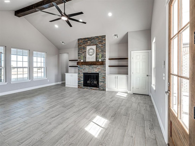 unfurnished living room with ceiling fan, a stone fireplace, beamed ceiling, high vaulted ceiling, and light hardwood / wood-style floors