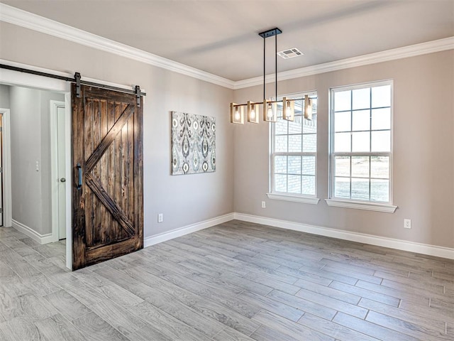 unfurnished room featuring a chandelier, a barn door, crown molding, and light hardwood / wood-style floors