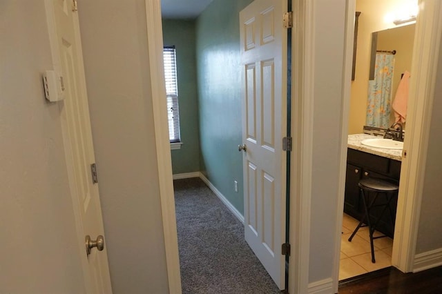 corridor with sink and dark colored carpet