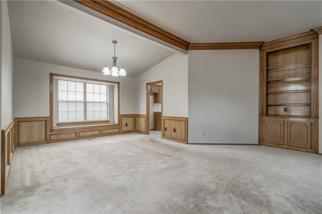 carpeted empty room featuring vaulted ceiling, an inviting chandelier, and crown molding