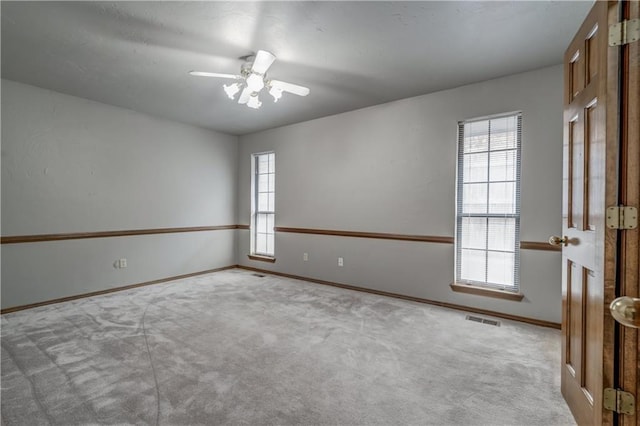 empty room featuring ceiling fan, a healthy amount of sunlight, and light carpet